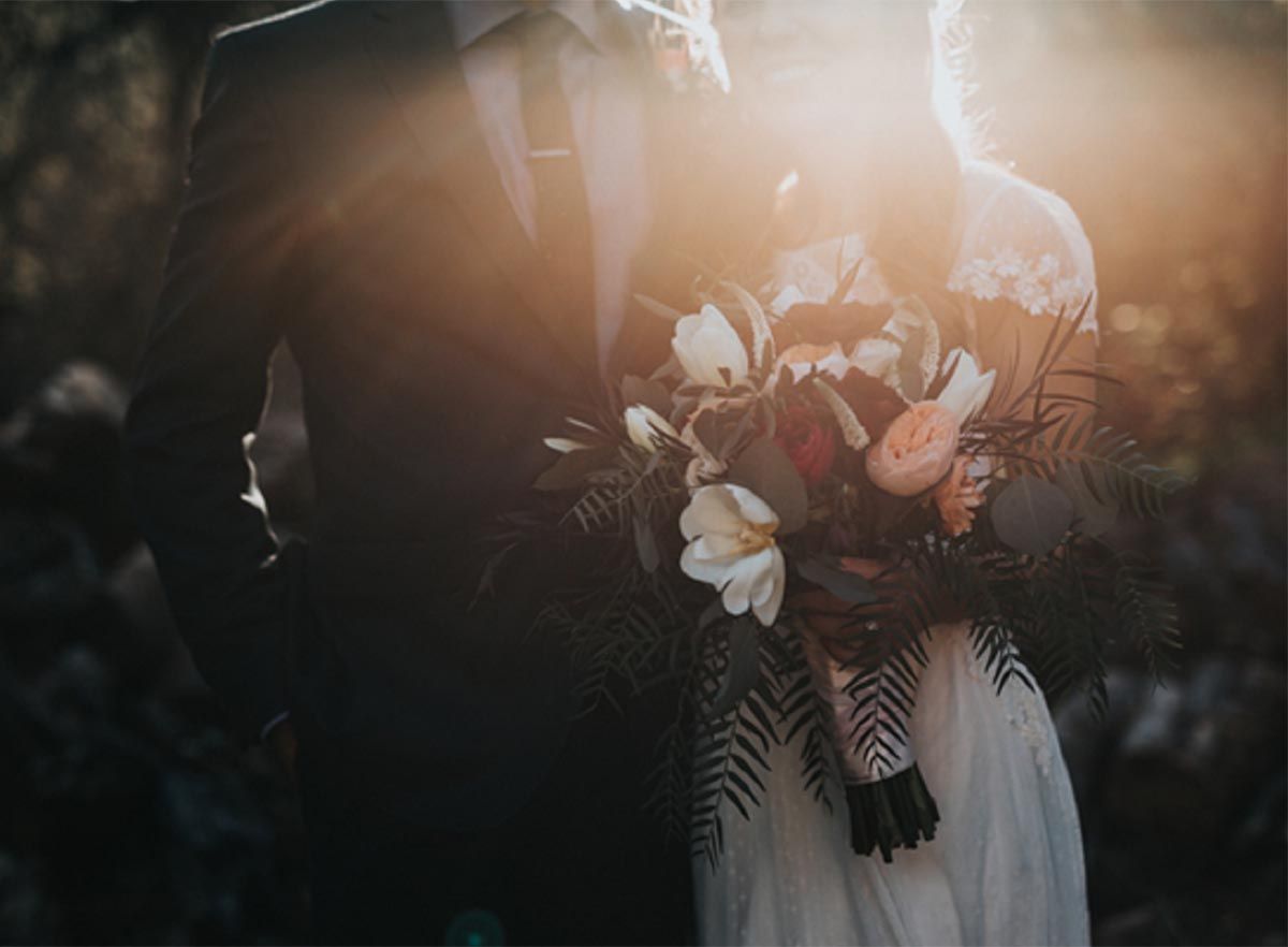 Wedding couple with flowers with sun rays shining on them